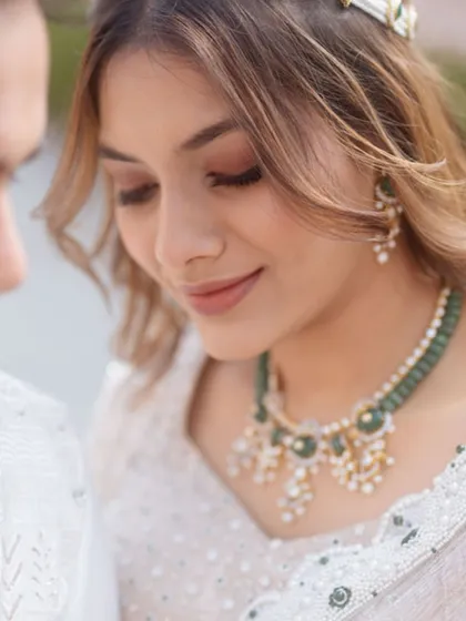 A close-up on the bride's soft makeup and beautiful green beaded necklace. This look is perfect for a daytime ceremony.