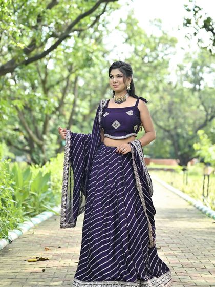 A model posing in the purple leheriya lehenga, showing how the dupatta can be draped for an elegant look.