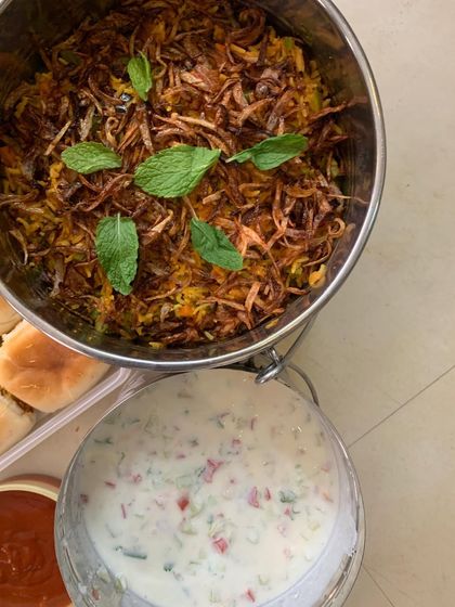 Aromatic Veg Biryani topped with fried onions and mint, served with Raita.