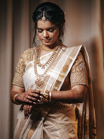 A classic three-quarter portrait of the bride. This shot beautifully showcases her intricate gold jewelry and the detailed embroidery on her blouse.