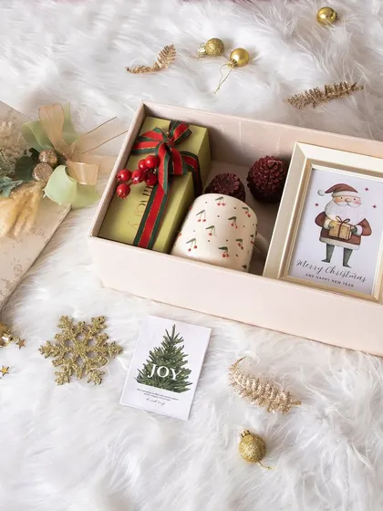 The Snowy Christmas Hamper is perfect for creating a festive mood. It includes a cherry mug, a Santa frame, and pine-scented candles.