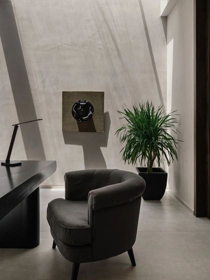 A quiet corner in the home office, featuring a sculptural armchair and a piece of abstract art. The space is designed to be minimal and calming, fostering focus and creativity.