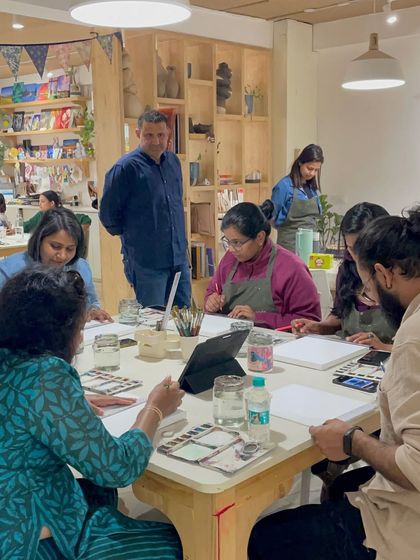 A wide shot of the studio during a busy workshop, with mentors walking around and assisting participants.