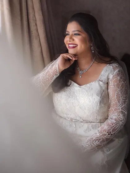 A candid moment of the bride looking out a window, her makeup looking soft and beautiful.