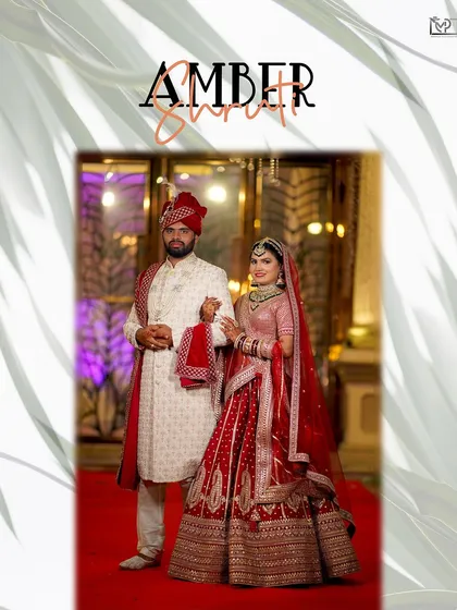 A classic wedding portrait of the couple on the red carpet. The bride's magnificent red lehenga and the groom's elegant sherwani are captured in their full splendor.