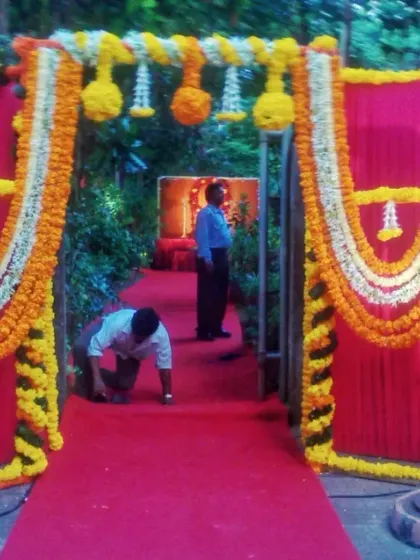 A simple yet festive entrance gate made with pink panels and decorated with garlands of white and yellow marigolds.