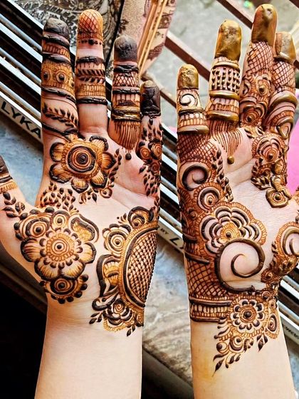 This designer style mixes and matches different elements. It combines floral motifs, circular mandalas, and intricate netting on the fingers for a creative and personalized mehendi look.