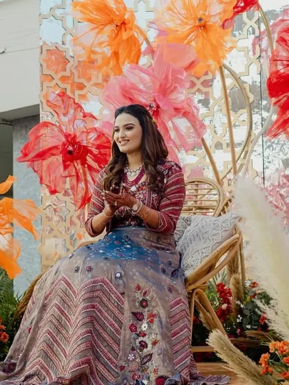 The bride enjoying her Haldi ceremony, with the textured paper flowers creating a stunning visual behind her.