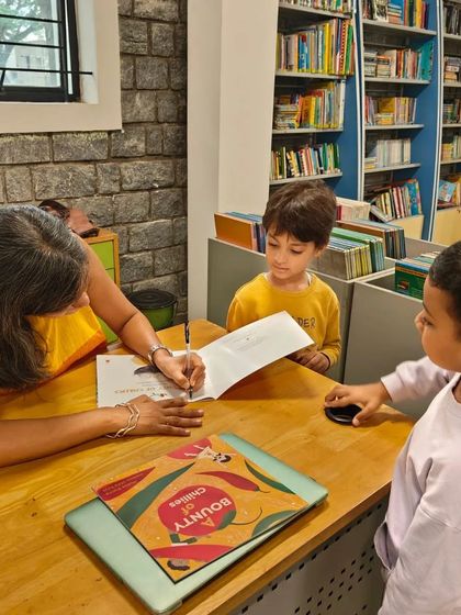 Two young boys eagerly watch as their book gets signed after the 'A Bounty of Chilies' launch.