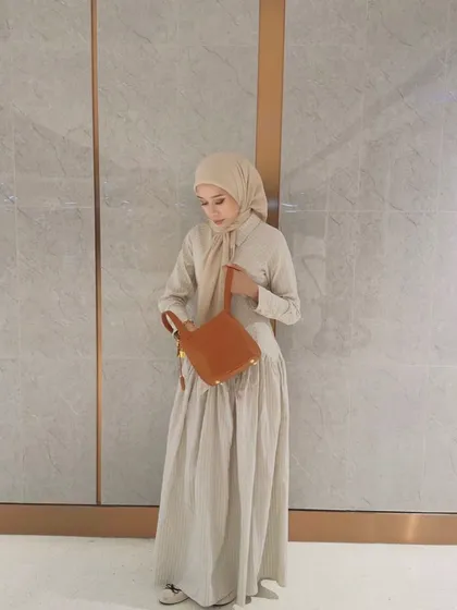 A customer looking elegant in a neutral outfit, perfectly complemented by the HerCharm Bucket Bag in LV brown. It shows how well the bag pairs with a long dress.