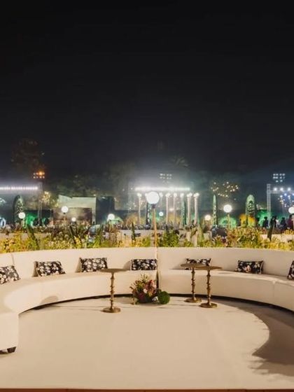 The clean, white curved sofas create a striking contrast against the dark night, providing a chic and inviting seating area for guests at the reception entrance.