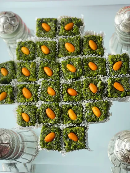 A close-up of the pistachio and almond mithai, beautifully arranged and surrounded by small silver containers.