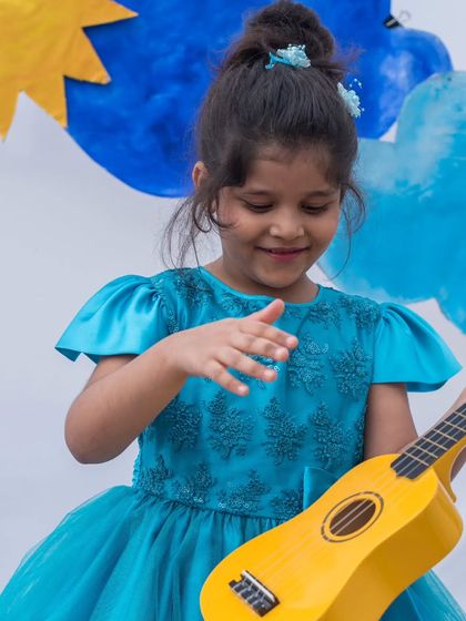 Strumming a happy tune in her blue party dress. The combination of a detailed bodice and a flowing tulle skirt makes this a wonderful choice for any festive event.