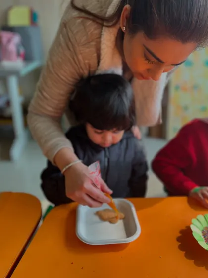 A parent helps her child decorate a cookie, a lovely moment of family bonding.