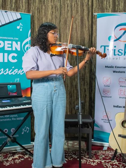 A student stands and plays the violin during an open mic session at the HSR branch.