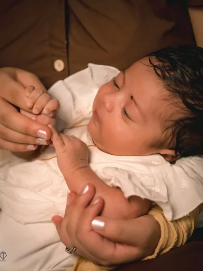 A sleeping baby gently holding her mother's finger. This image captures the instinctive connection and trust between a mother and her child.