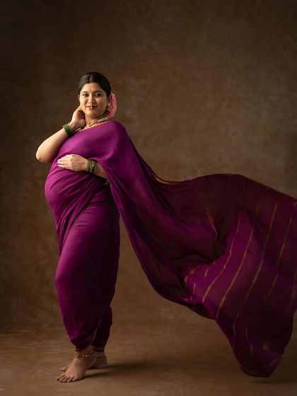 A full-length portrait showing the beautiful drape and flow of this traditional purple saree, creating a graceful and elegant silhouette.