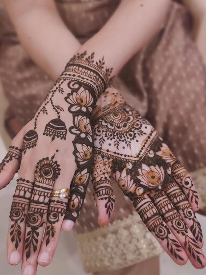 An elegant Indo-Arabic fusion design. One hand features a trail of lotuses and jhumkas, while the other has a fuller pattern, creating a beautiful and modern asymmetrical look.