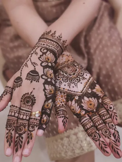 A stunning design with lotus flowers and jhumkas. The way the lotus vine trails down one side is a mix of Indian and Arabic styles.