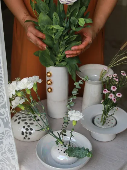 An assortment of white porcelain vases from the 'Celebrations' collection, some with gold accents and others with playful polka dots, perfect for floral arrangements.