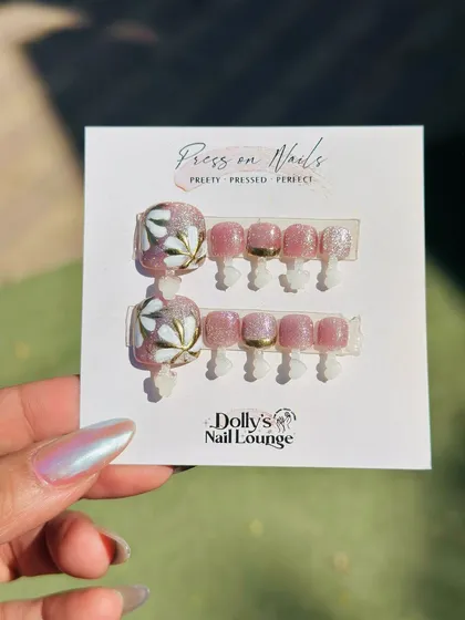 A lovely floral press-on set for toes, combining a shimmery pink base with hand-painted white and gold flowers.