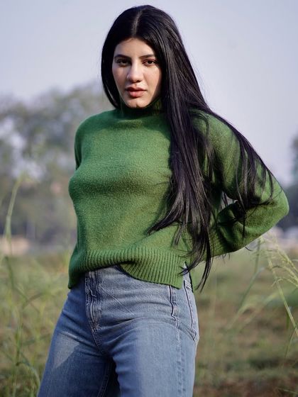 An outdoor fashion shoot in a natural setting. The contrast between the green field and the model's sweater creates a vibrant, eye-catching portrait.