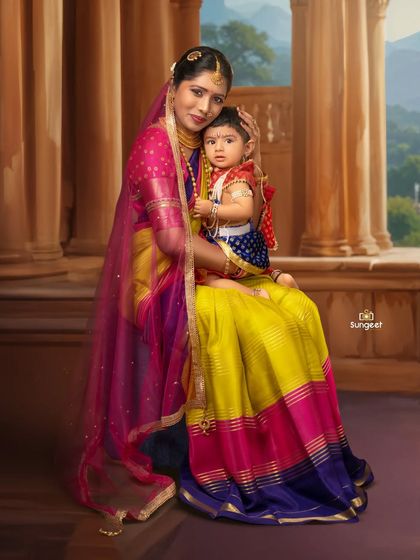 A mother and child portrait with a classic, painterly feel. Dressed in vibrant traditional clothing, they are posed against a backdrop that resembles a palace balcony, giving the image a royal and timeless quality.