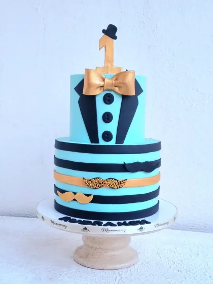 A "little man" themed cake for a first birthday. This design uses simple fondant cutouts to create a shirt and bow tie, plus a striped pattern with mustache accents.