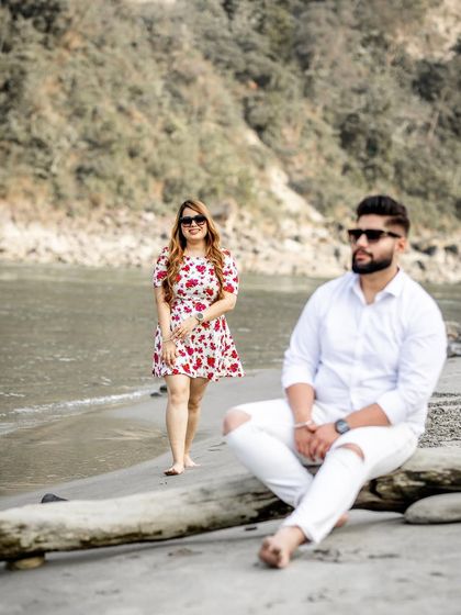 A candid and stylish shot from a pre-wedding session by the river, capturing the couple in a relaxed and fashionable pose.