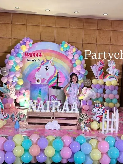 A wider view of the unicorn party setup, showing the full stage and floor balloon decor that creates a whimsical and colorful atmosphere for a 5th birthday celebration.