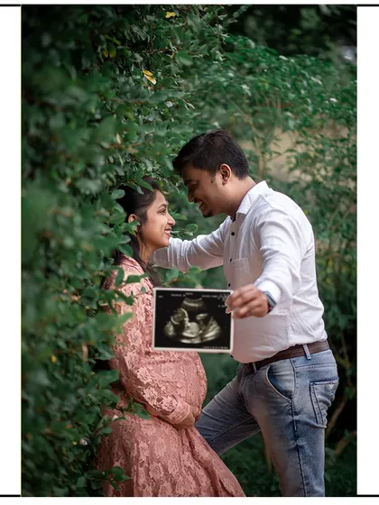 The dad-to-be proudly holds up the sonogram picture, sharing the joy with his partner.