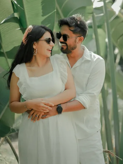 A playful and loving embrace amidst lush greenery. The couple's sunglasses and bright smiles give this candid shot a fun, relaxed vibe, perfect for a sunny day shoot in Pune.