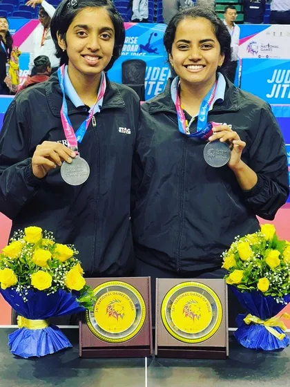 Kushi V and her partner proudly display their silver medals from the 36th National Games in Gujarat. This achievement in the Women's Doubles category is a highlight of her competitive career.