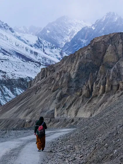 A lone traveler walking along a desolate road in Spiti, dwarfed by the immense landscape. This image evokes a sense of solitude and personal journey amidst the grandeur of the Himalayas.