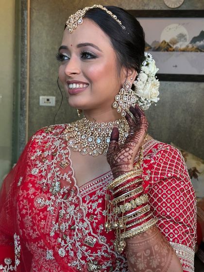 A three-quarter view of the bride, showing how the floral bun and maang tikka work together.