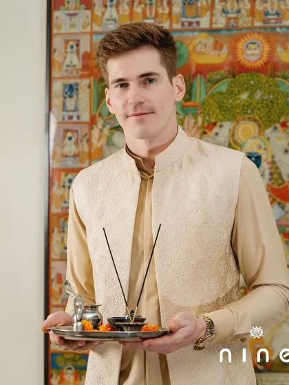 A festive moment, ready for a pooja. This beige vest with subtle embroidery, paired with a matching kurta, is a perfect ensemble for traditional ceremonies and family celebrations.