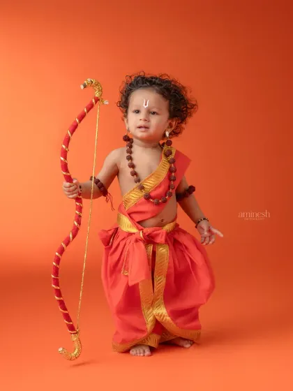 Celebrating Ram Navami with a powerful portrait of a child dressed as Lord Ram. Holding a bow and arrow against a vibrant orange backdrop, this image captures the divine and courageous spirit of the theme.