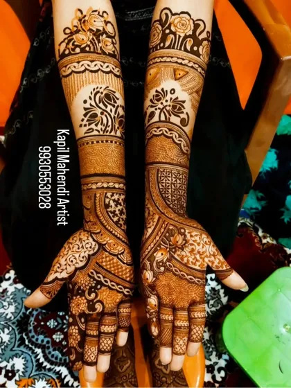 This is a classic full-arm mehendi style with matching symmetrical patterns on both hands. The design features floral bands and detailed work on the fingers for a complete look.