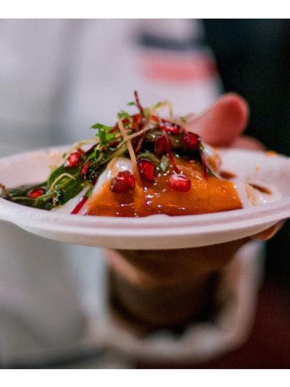 A chef holds a perfectly plated serving of modern Indian chaat, garnished with pomegranate and microgreens. This image, a duplicate of ID 32 and 12, is a strong representation of our culinary style.