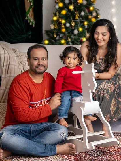 A beautiful family portrait, with their little one enjoying a ride on the white rocking horse.