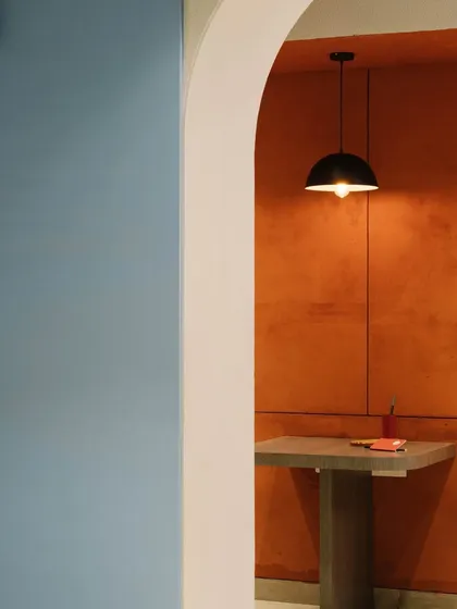 A view through an archway reveals the contrast between the cool blue of the pantry area and the warm red of a breakout nook, showcasing our use of color blocking to define space.