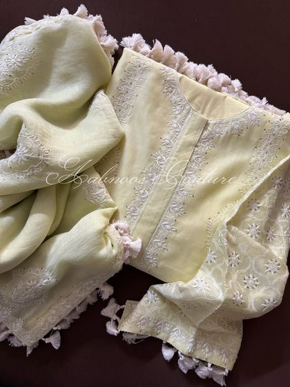 A flat-lay of the lemon yellow kurta set, showing the coordinated kurta and soft mul dupatta, both finished with charming tassels.