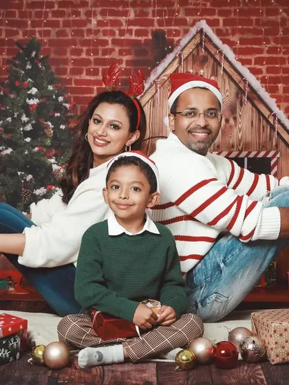A classic family Christmas card photo. Sitting back-to-back against a festive brick wall backdrop, this family looks picture perfect.