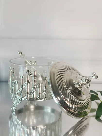 The lid is off, showing the simple glass pot held within the ornate silver frame. This piece is a beautiful example of how utility can be elevated with artistic design.