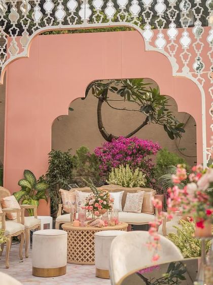 Another view of the photo corner, showcasing the beautiful contrast between the delicate jali screen, the soft pink wall, and the lush greenery.