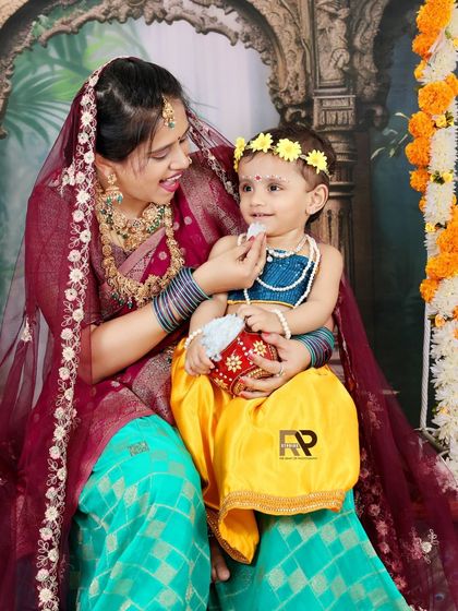A mother dressed as Yashoda shares a sweet moment with her daughter, dressed as Radha. This photo from a Krishna-themed session is full of love and cultural significance.