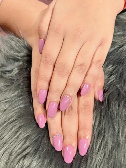A soft lilac polish on oval nails, with a delicate line of rhinestones at the cuticle of the accent nail for a subtle touch of sparkle.