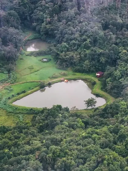 An aerial photograph of the man-made, heart-shaped lake at Mookanana Resort in Sakleshpur, a hidden gem in the Western Ghats.