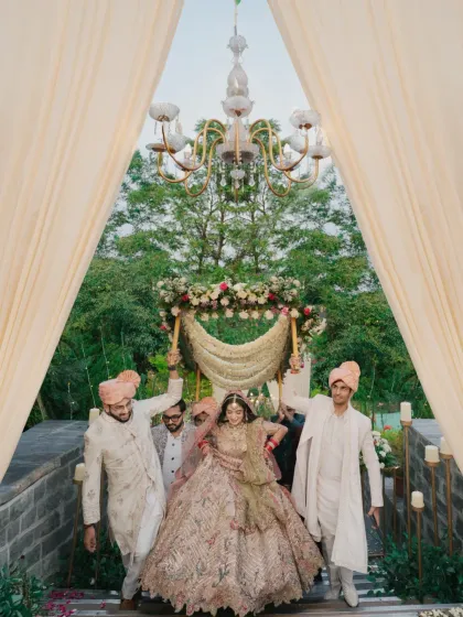 The bride's grand entrance, walking down a stone staircase under a floral canopy, looking like royalty.