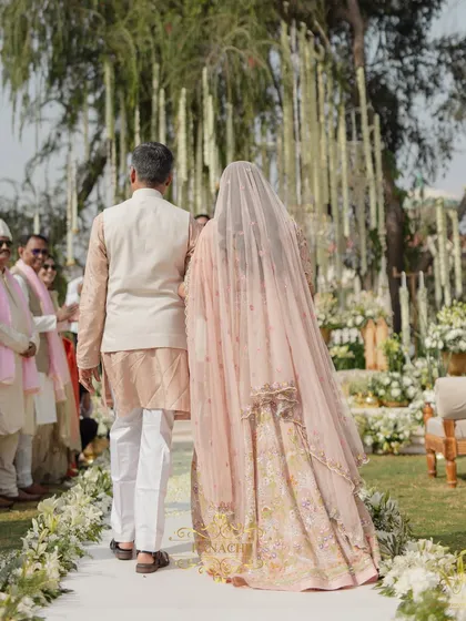 A view from behind as the father leads his daughter towards the mandap, a symbolic journey towards her new life.